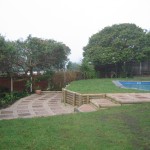 Paved entrance area and wooden retainer around pool